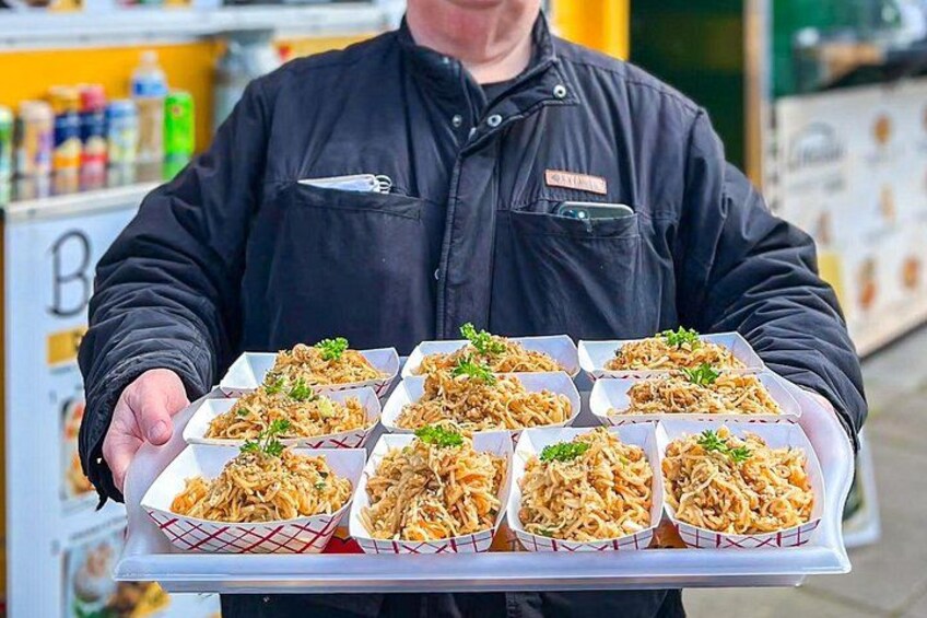 A person holding a tray with multiple containers of food. 1