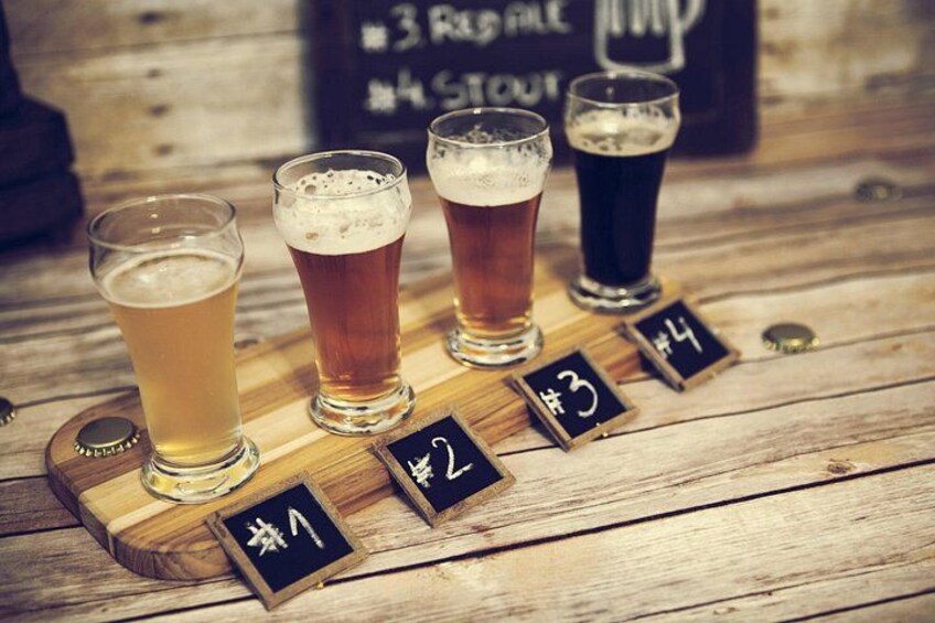 Four glasses of beer on a wooden table with numbered labels. 1