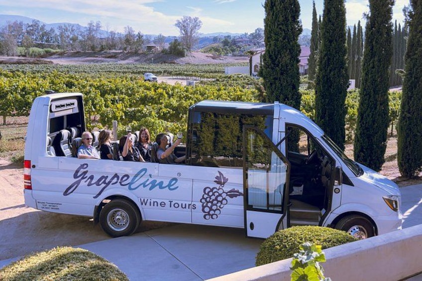 A white van with 'Grapeline Wine Tours' branding parked in a vineyard. 3