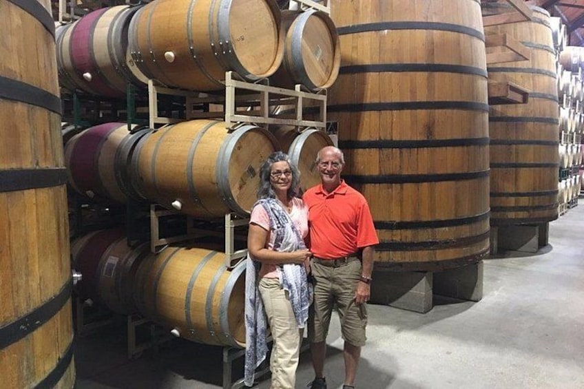 A person standing in front of large wooden barrels, likely in a storage or aging facility. 3