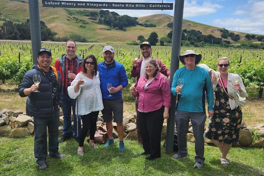 A group of people standing in a vineyard with a sign that reads 'Lafond Winery and Vineyards - Santa Rita Hills - California'. 4