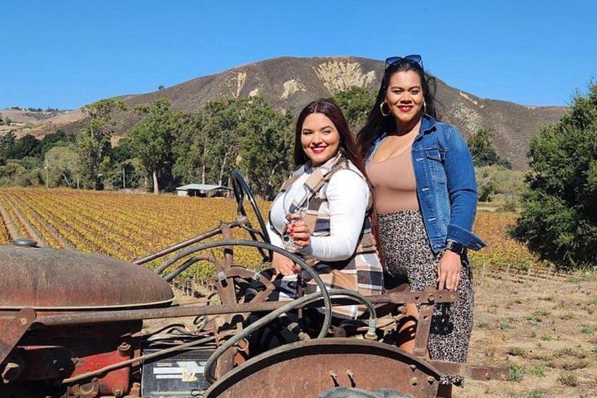 Two people standing next to a tractor in a field with mountains in the background. 5