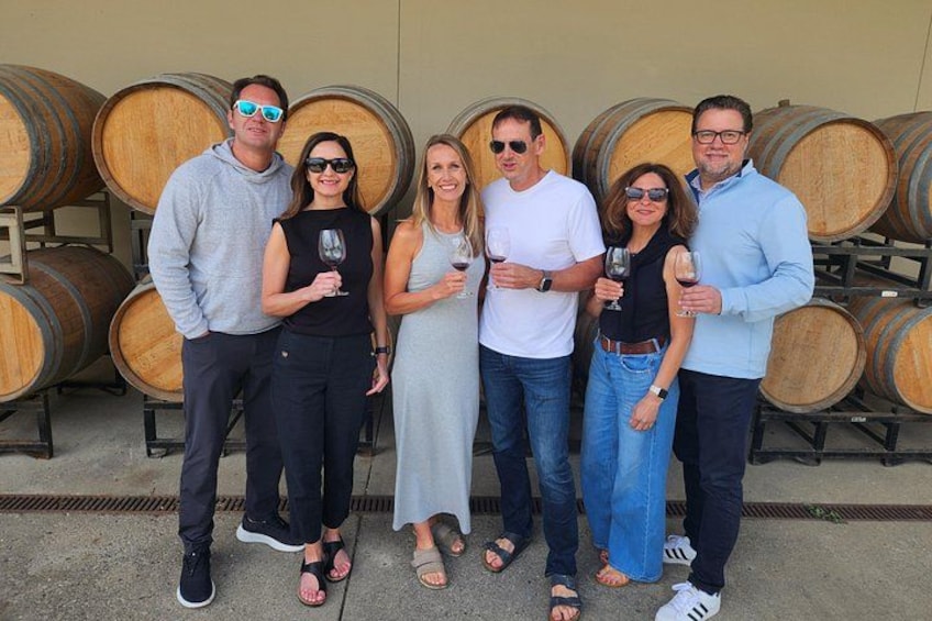A group of people standing in front of wine barrels. 3