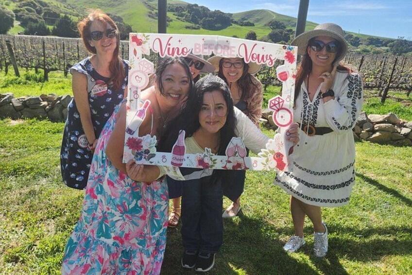 A group of people holding a sign with 'Vino Boreal Vows' written on it, standing in a vineyard. 2