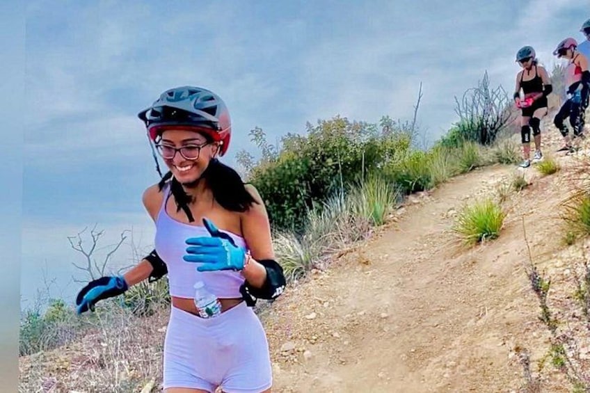 Una persona con casco y equipo de ciclismo pedaleando por un sendero de tierra bordeado de vegetación. 5