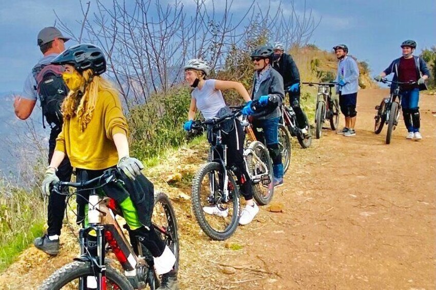 A group of cyclists on a dirt trail with trees in the background. 4