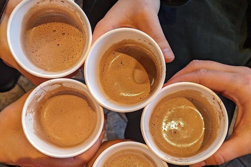 Manos sosteniendo cuatro tazas blancas de café. 2