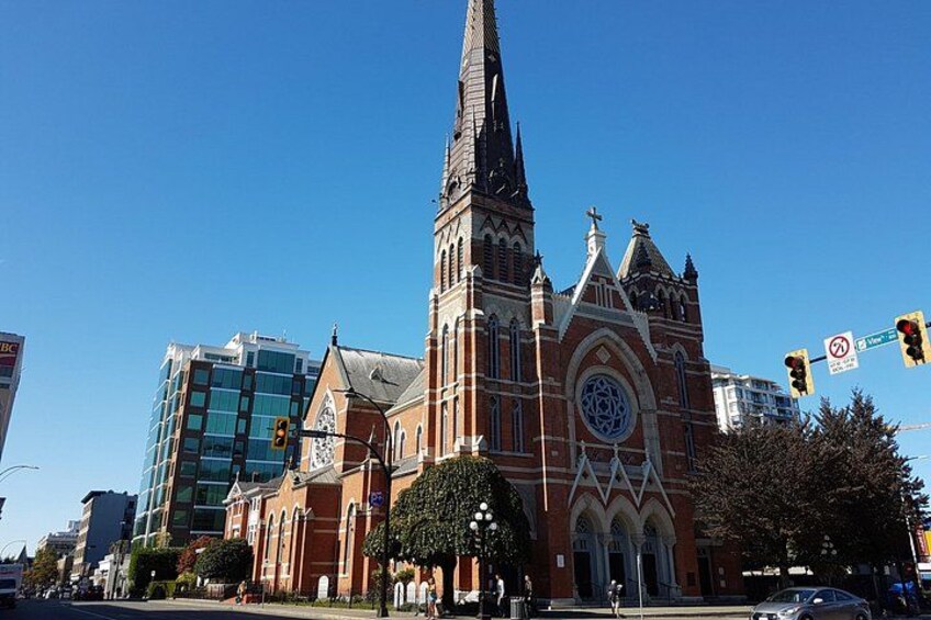 A historic church with a tall spire, a modern building with glass windows, and a traffic light. 4