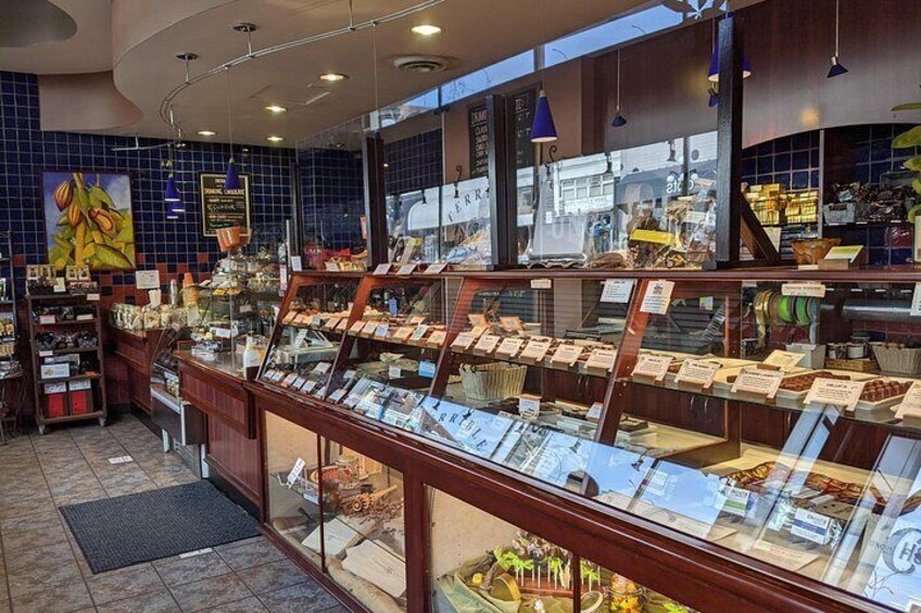 Una panadería con un expositor de pasteles y una barra repleta de productos horneados. 4