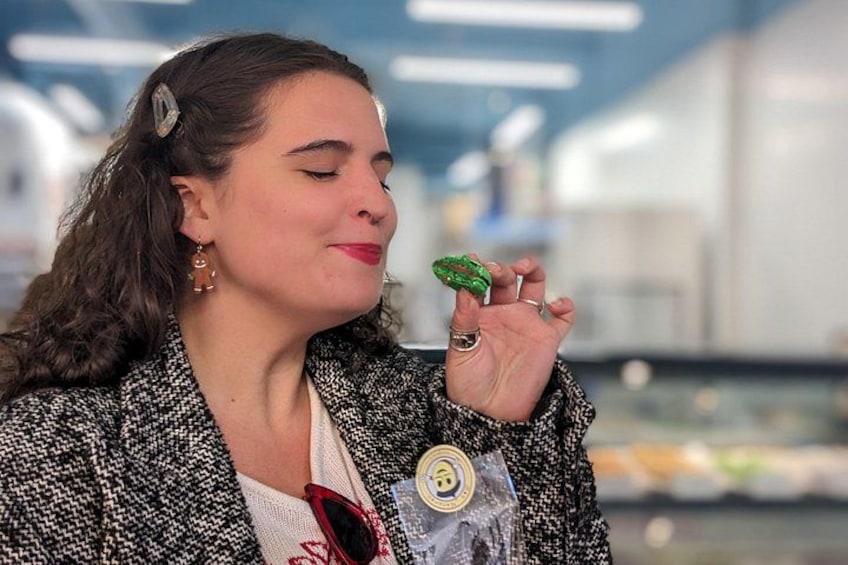 A person wearing a patterned jacket with a visible button, holding a green object. 1