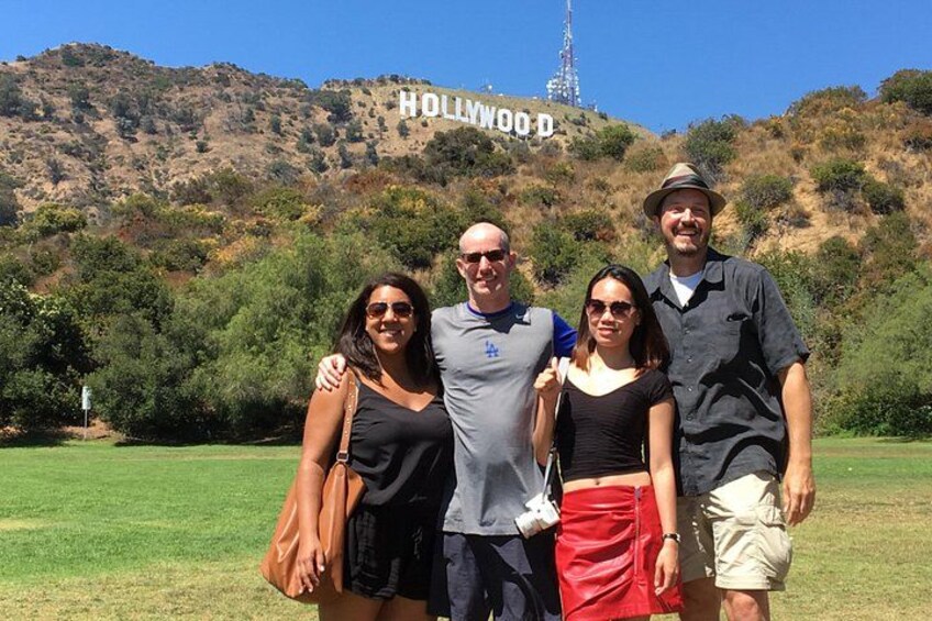 Un groupe de personnes se tient devant le panneau Hollywood, avec un paysage vallonné en arrière-plan. 5