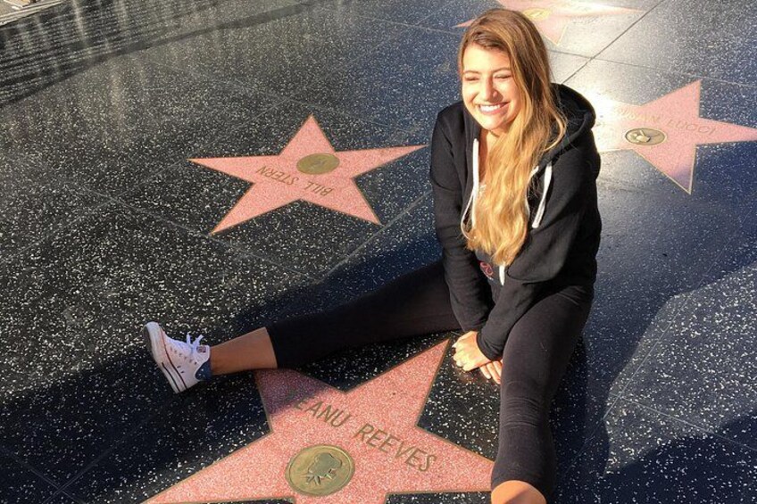 Une personne assise sur le « Hollywood Walk of Fame », avec les étoiles incrustées dans le trottoir visibles en arrière-plan. 4