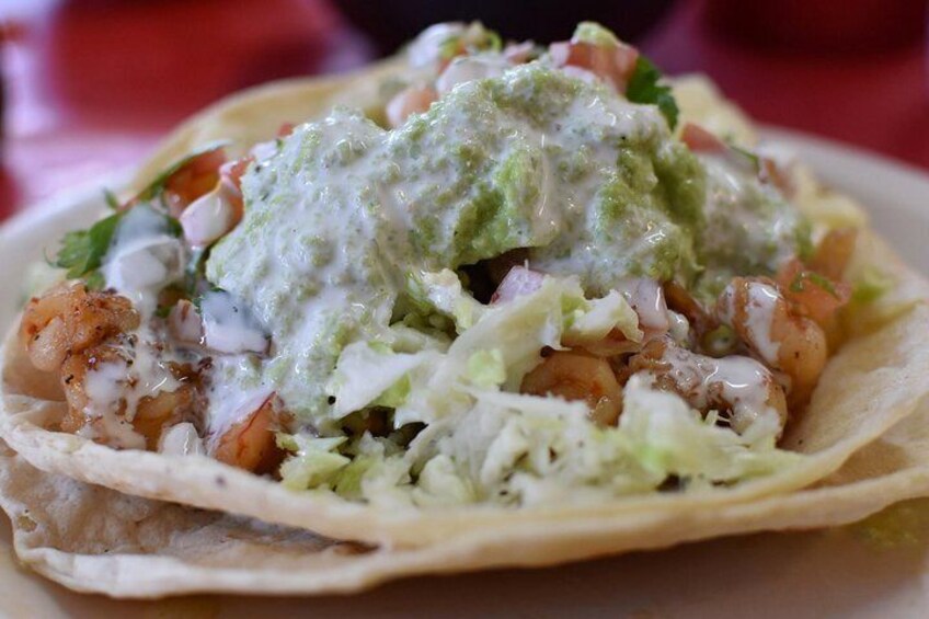 A taco with shrimp, lettuce, and a green sauce. 3