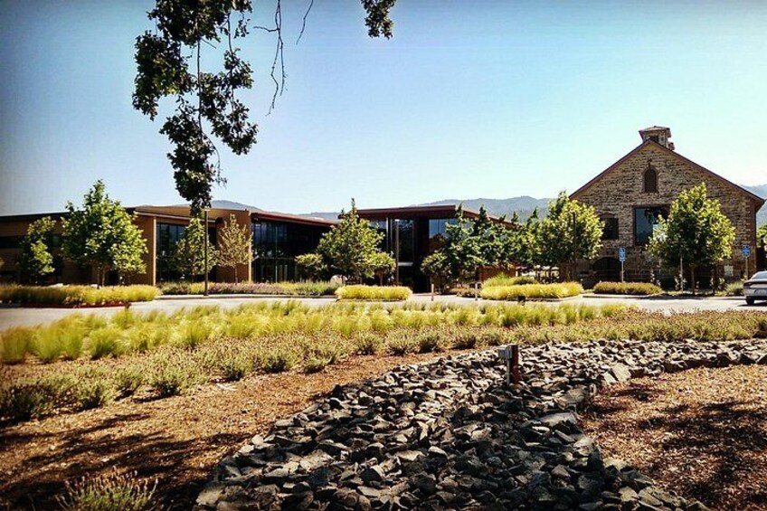 A modern building with a stone facade, surrounded by landscaped gardens and a clear sky. 4