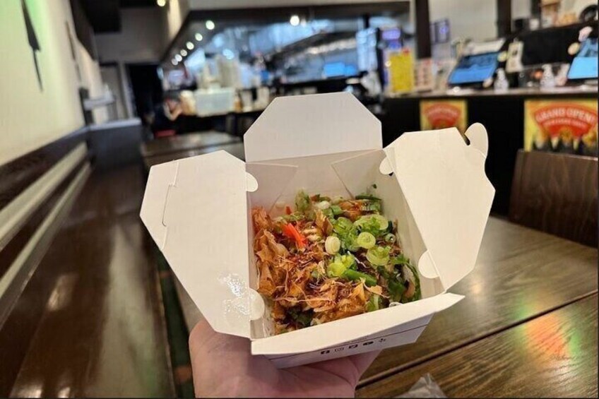 A person holding a takeout box with a salad. 2