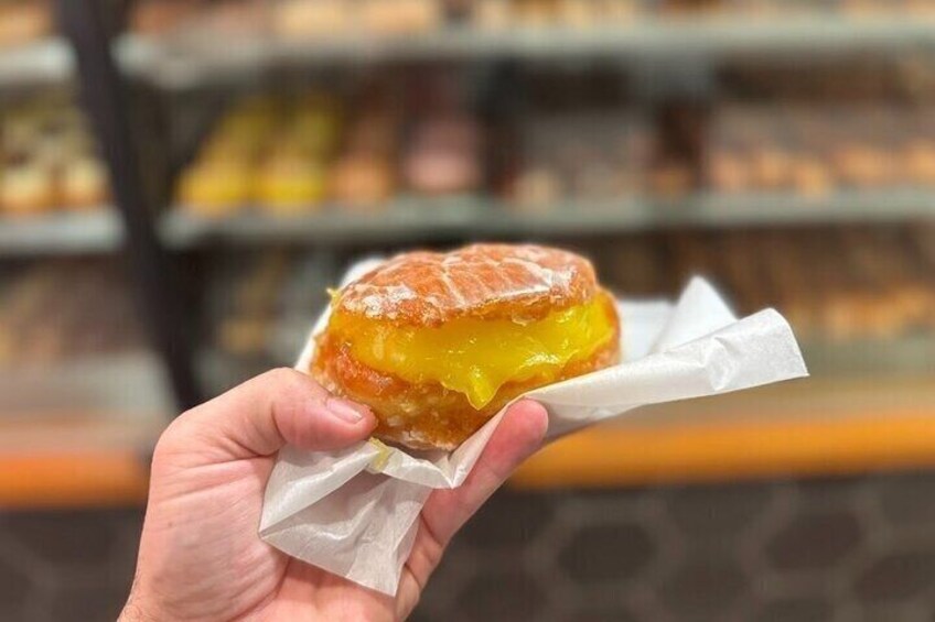 A hand holding a glazed donut with a white paper wrapper. 3