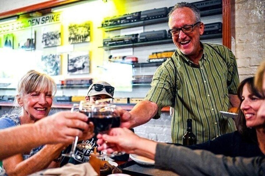 A group of people toasting with drinks at a bar with a 'Golden Spike' sign in the background. 1