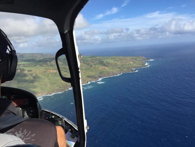 A helicopter cockpit with a view of a coastline and ocean. 5