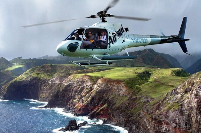 Een helikopter vliegt boven een kustlandschap met kliffen en de oceaan. 5