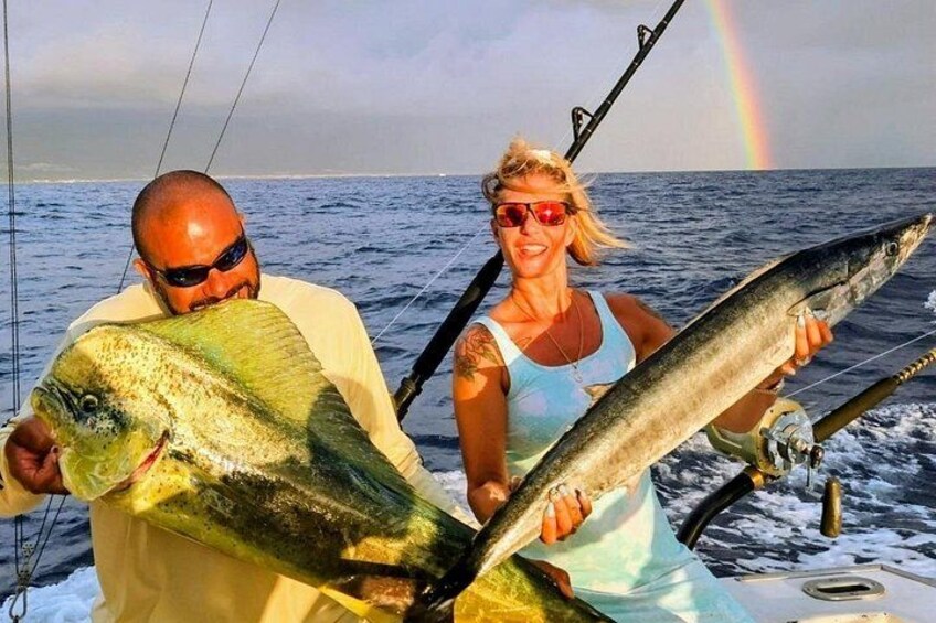Twee personen in een boot met grote vissen, een regenboog op de achtergrond. 2