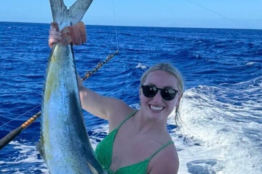 En person som håller i en stor fisk på en båt ute på havet. 3