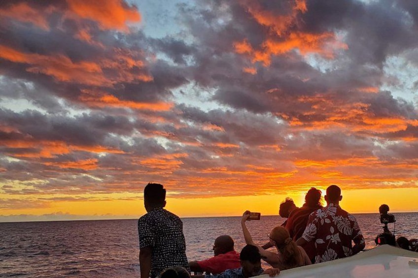 A sunset over the ocean with a group of people on a boat. 2