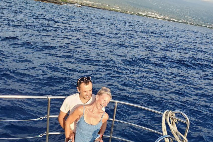 Two people on a boat with a railing, water, and a distant shoreline. 3