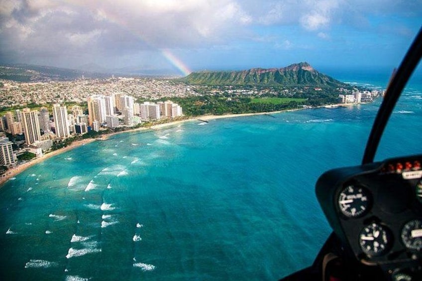 A helicopter view of a coastal city with a mountain in the background and a rainbow. 2