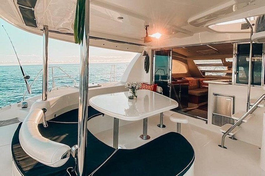 L’intérieur d’un bateau, avec un coin repas, un espace salon doté de sièges confortables et une vue sur la mer. 1