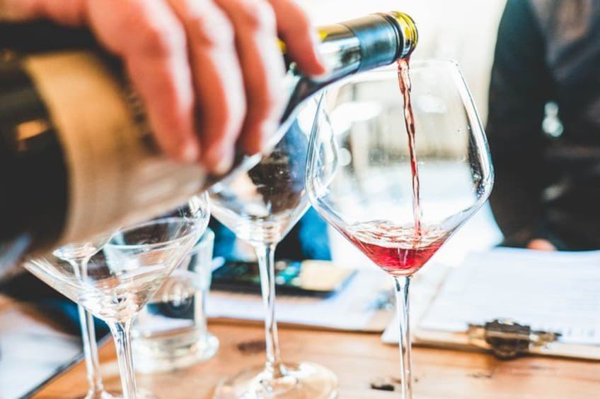 A person pouring wine into a glass. 5