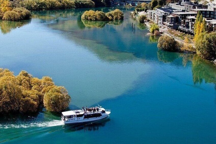 Un barco en un río con edificios y árboles a lo largo de las orillas. 4
