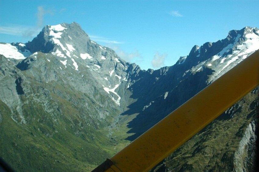 A mountain range with snow-capped peaks, a clear sky, and a yellow object in the foreground. 4