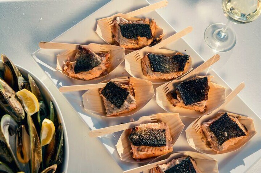 A plate of salmon tartare with black caviar on toothpicks, accompanied by a bowl of oysters and lemon wedges. 5