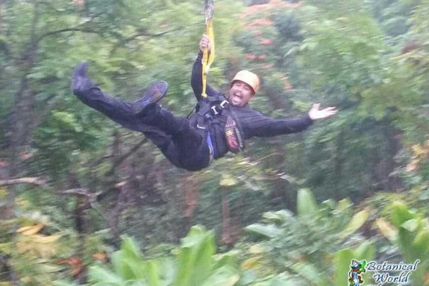 A person bungee jumping with a harness and helmet, surrounded by dense green foliage. 2