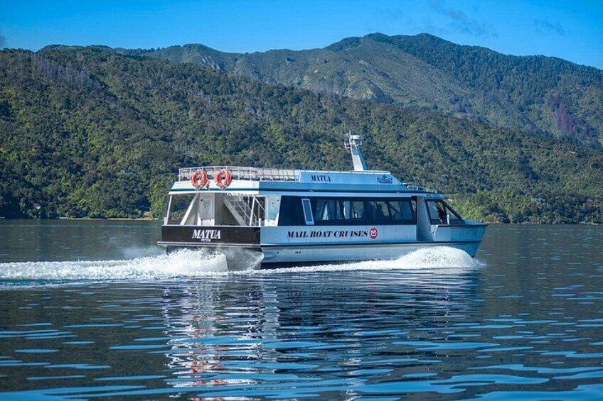 A boat named 'MATUA' on a lake with mountains in the background. 4