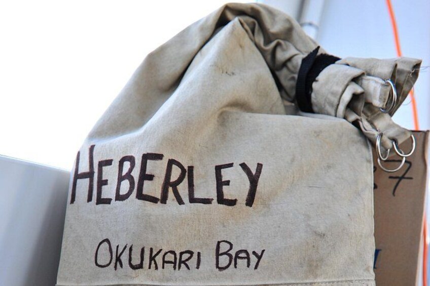 A beige bag with 'HEBERLEY' and 'OKUKARI BAY' written on it. 3
