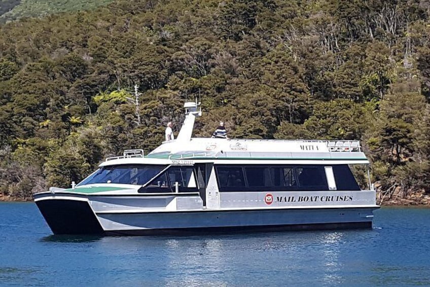 A white and green mail boat cruise with a cabin, moving on a calm body of water. 4