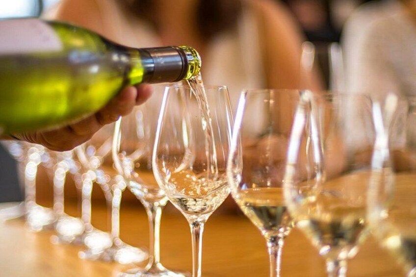 En person som häller upp vin i flera glas på ett bord. 2