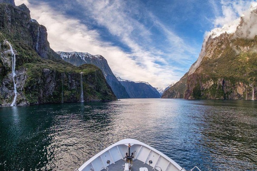 Un bateau sur un lac paisible, avec des cascades et des montagnes en arrière-plan. 5
