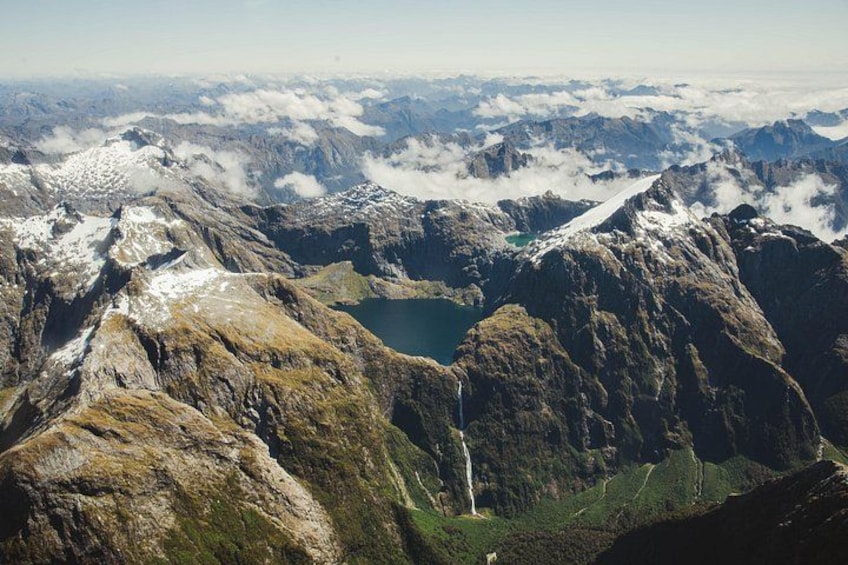 Un paysage montagneux avec un lac, une cascade et un sommet enneigé. 3
