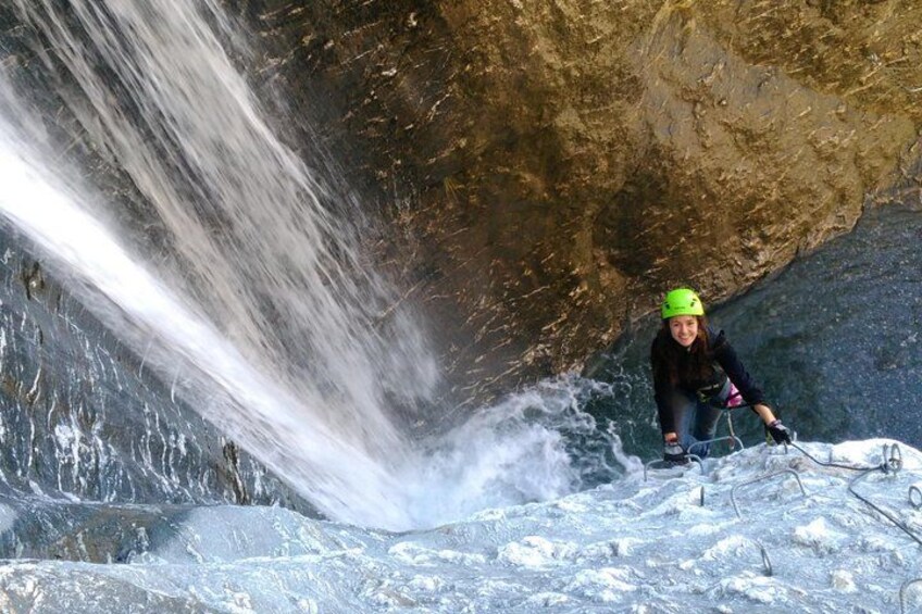A person rappelling down a waterfall in a rocky cave environment. 4