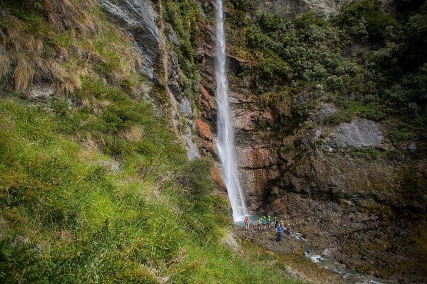 A waterfall cascading down a rocky cliff surrounded by greenery. 2