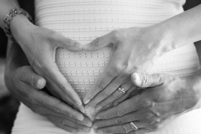 Una mujer embarazada sosteniendo su vientre con un contorno de corazón dibujado en él. 3