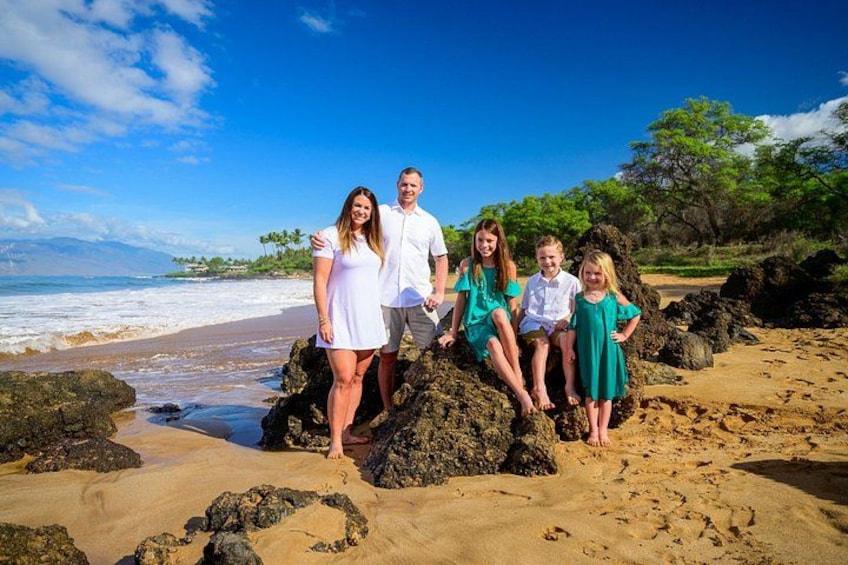 Una familia en una playa rocosa con olas del océano al fondo. 5