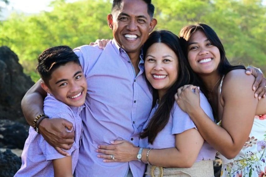 Una familia de cuatro disfruta del aire libre con vegetación al fondo. 1