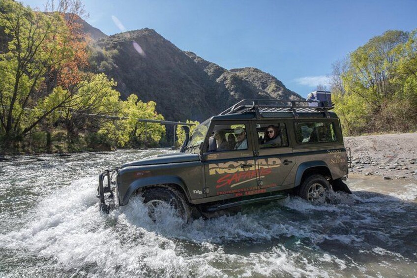 A vehicle navigating a river surrounded by mountains. 3