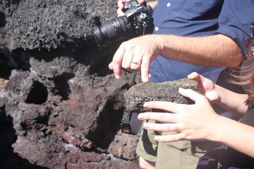 A person holding a camera and a rock, possibly taking a photograph. 4