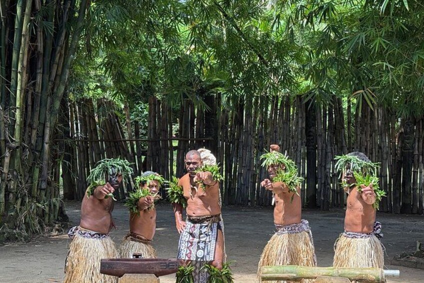A group of people in traditional attire with plants on their heads, standing in a bamboo forest. 3