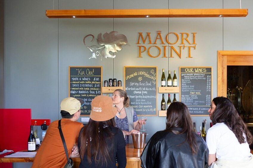 Eine Bar mit einem Schild, auf dem 'MAORI POINT' steht, und einer Speisekarte, die Getränke und Spezialitäten auflistet. 2