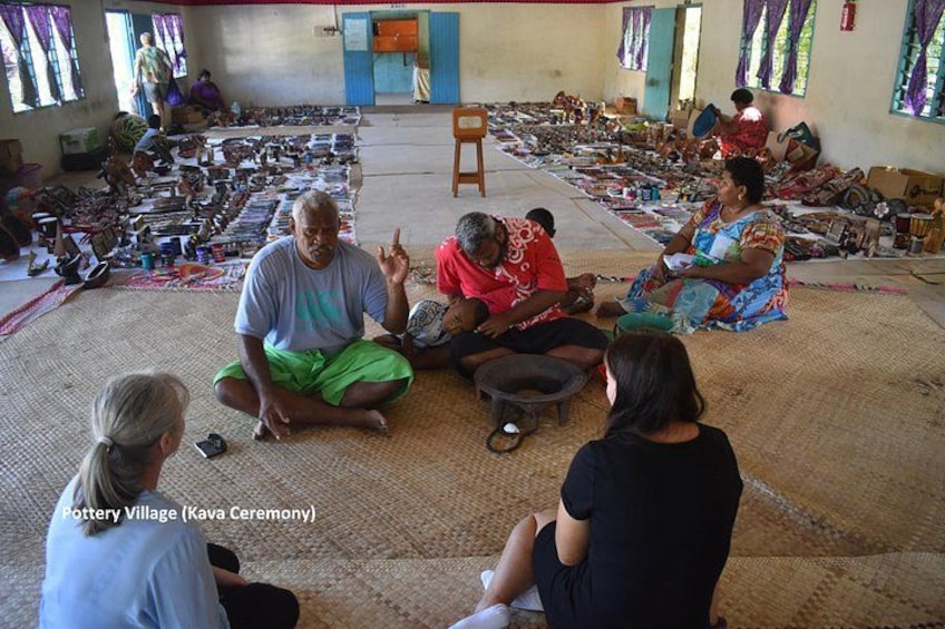 A pottery village with people sitting on the floor, surrounded by pottery items. 2
